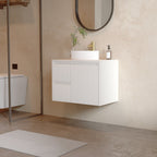 A modern floating bathroom vanity with a white ribbed cabinet, a white rectangular sink, and a gold faucet, shown in a minimalist beige-toned bathroom setting.